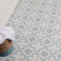 a bathroom with blue and white tiles on the floor next to a basket full of towels