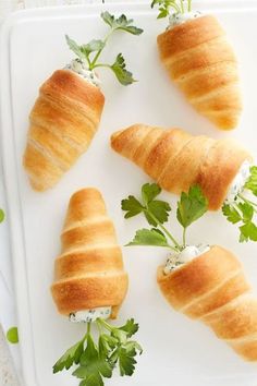 four croissants on a white tray with green garnish and parsley