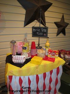 a table with popcorn, candy and movie time signs on it in front of a wall