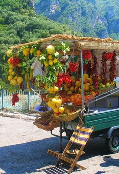 an outdoor fruit cart with fruits and vegetables on display in front of a mountain range