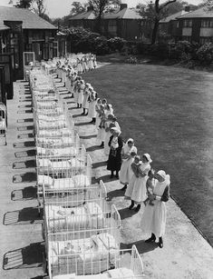 an old black and white photo of women standing in front of baby cribs