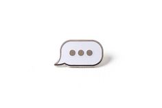 a white speech bubble pin with two brown dots