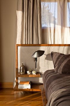 a bed sitting in a bedroom next to a window with drapes on the windowsill