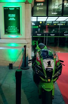 a motorcycle parked in front of a building with green lights on it's side