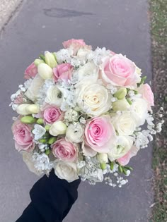 a bridal bouquet in someones hand on the street with no one around it