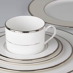 a white cup and saucer sitting next to each other on top of silver plates