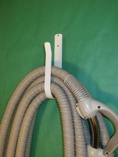 two hoses connected to each other in front of a green wall with white piping