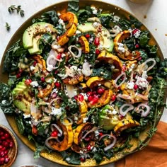 a salad with onions, kale, and other vegetables on a plate next to some pomegranates