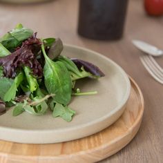 a plate filled with greens on top of a wooden table