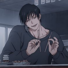 a man sitting at a table with chopsticks in his hand and eating food