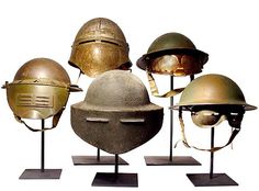 five different types of helmets displayed on metal bases, all in various colors and sizes