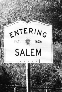 black and white photograph of a sign for salem, with trees in the back ground