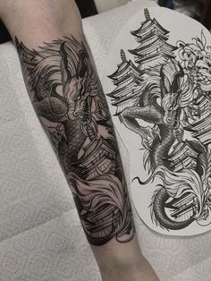 a man's leg with tattoos on it next to a plate that has an image of a dragon