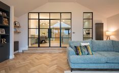 a living room with a blue couch and wooden floors in front of a glass door