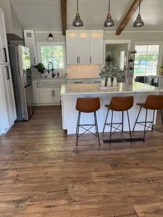 three stools sit at the center of a kitchen island in front of an open floor plan