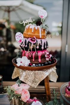 a three tiered cake with pink and black icing on it's side