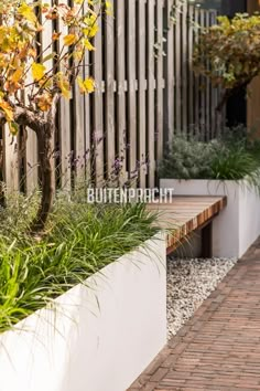 a wooden bench sitting next to a white planter filled with purple and yellow flowers