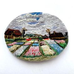 a round patch with an image of a farm in the distance and clouds above it