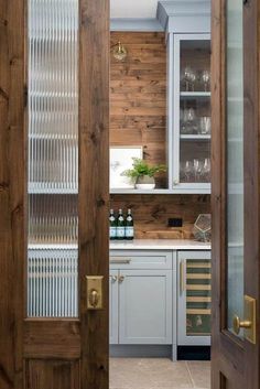 an open door leading to a kitchen with wine glasses on the counter and cabinets behind it