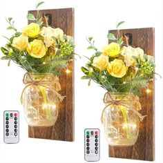 two vases with yellow flowers and lights are on the wall next to a remote control