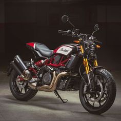 a red and black motorcycle is parked in a dark room with lights on it's sides