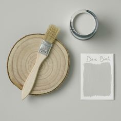 a paint brush sitting on top of a piece of wood next to a white paper