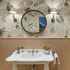 a white sink sitting under a bathroom mirror next to a wall mounted faucet