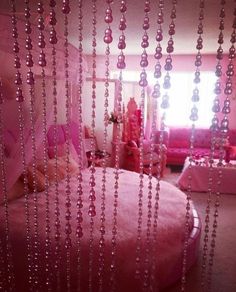 a pink bedroom with beads hanging from the ceiling