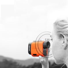 a woman is looking into the distance with an orange camera