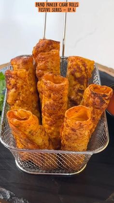 some food is in a metal basket on a black tray and garnished with toothpicks