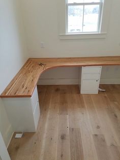 an empty room with a wooden desk and white drawers