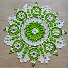 a green and white doily on a wooden surface with flowers in the center,