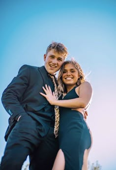 a man and woman hugging each other in front of the sky with their arms around each other