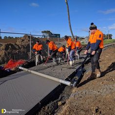 men in orange shirts are working on a construction site