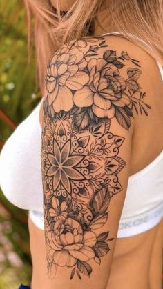 a woman's arm with flowers and leaves tattooed on the back of her shoulder