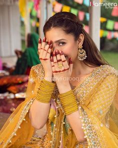 a woman in yellow dress holding her hands up to her face