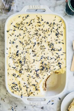 a casserole dish filled with cheese and lavender sprinkles on a marble table