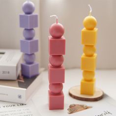 two candles sitting next to each other on top of a white table with an open book