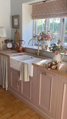 a kitchen with pink cabinets and flowers on the window sill in front of the sink