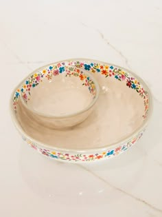 two bowls with floral designs on them sitting on a white counter top next to each other