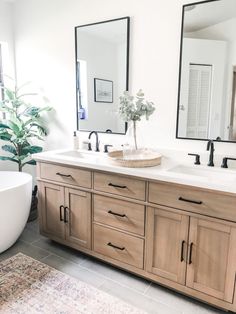 a bathroom with two sinks, a bathtub and large mirrors on the wall above it