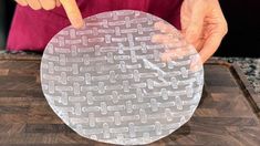 a person pointing at a piece of plastic on top of a cutting board