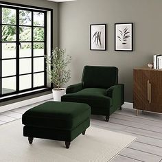 a green chair and ottoman in front of a large window with black framed pictures on the wall