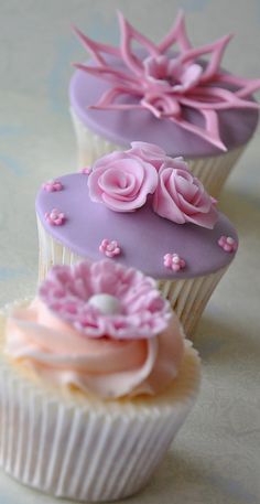 three cupcakes decorated with pink and purple frosting