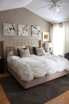 a large bed sitting in the middle of a bedroom next to two paintings on the wall