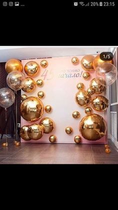 gold balloons are hanging from the ceiling in front of a white wall