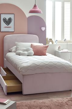 a pink and white bedroom with a bed, dressers, and other items in the room