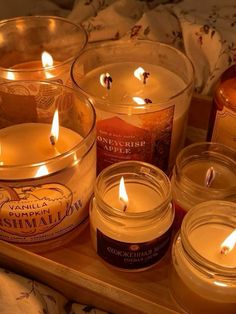 several candles are sitting in glass containers on a tray