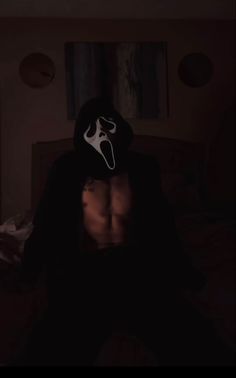 a shirtless man wearing a mask in the dark