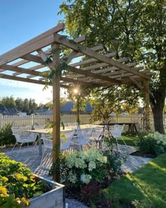 an outdoor dining area with tables and chairs under a pergolated arbor, surrounded by flowers